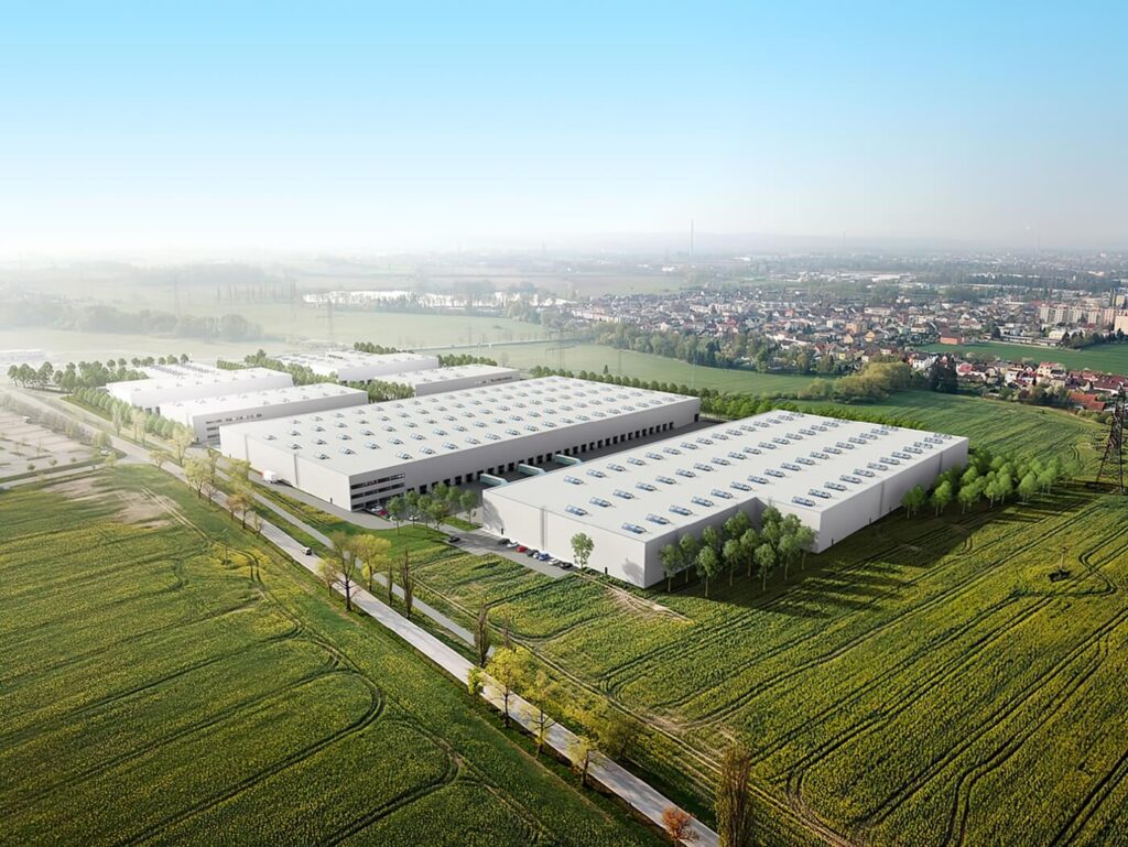 Letecký 3D zákres moderního skladového komplexu do reálné krajiny při západu slunce s detailním nasvícením hal a okolní infrastruktury.